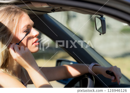 Woman applying mascara in car Woman applying mascara in car 128946126