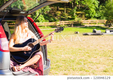 Hippie woman playing guitar in van car 128946129