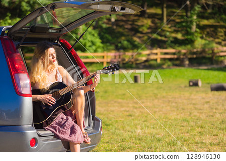 Hippie woman playing guitar in van car Hippie woman playing guitar in van car 128946130