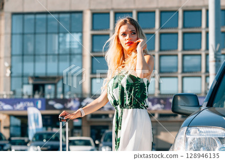 Woman with suitcae on city street 128946135
