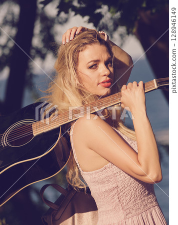 Woman playing acoustic guitar in park Woman playing acoustic guitar in park 128946149