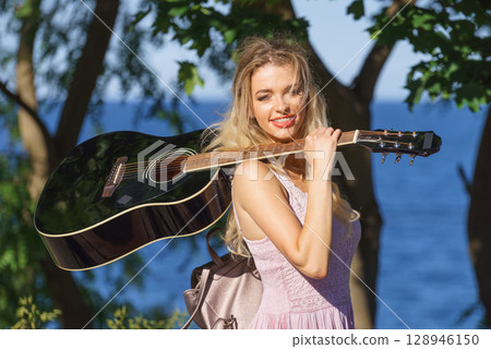 Woman playing acoustic guitar in park Woman playing acoustic guitar in park 128946150