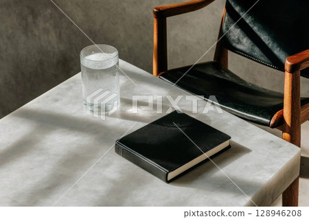Journal on marble table with glass of water casting shadows, modern minimalism 128946208