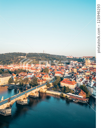 Morning light bathes Prague in golden hues, showcasing a stunning aerial view of the historic city. 128946293