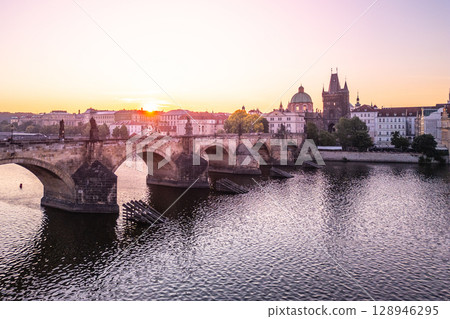 Morning light casts a warm glow over Charles Bridge, highlighting the historic architecture of Prague. The Vltava River reflects this serene atmosphere, presenting a tranquil cityscape. Morning light casts a warm glow over Charles Bridge, highlighting the historic architecture of Prague. The Vltava River reflects this serene atmosphere, presenting a tranquil cityscape. 128946295