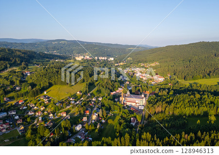 Tanvald offers a stunning aerial perspective, showcasing its lush greenery and architecture. The surrounding Jizera Mountains create a picturesque backdrop in Czechia during the day. 128946313