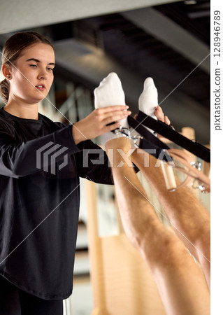 Instructor guiding a student's legs during a fitness workout session Instructor guiding a student's legs during a fitness workout session 128946789