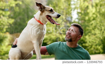Man enjoying outdoor time with his dog in a park setting Man enjoying outdoor time with his dog in a park setting 128946793
