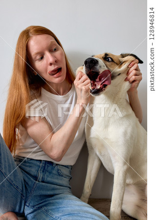 Woman Making Funny Faces with a Playful Dog Indoors Woman Making Funny Faces with a Playful Dog Indoors 128946814