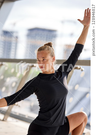 Young woman practicing fitness stretching poses in an urban environment 128946817