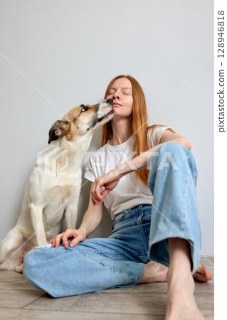 Young woman enjoying time with her dog in a cozy home setting Young woman enjoying time with her dog in a cozy home setting 128946818