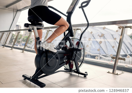 Person training on an air bike in a modern fitness studio 128946837