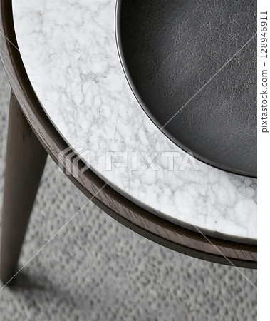 A wooden table with a marble top and a black plate on top of it 128946911