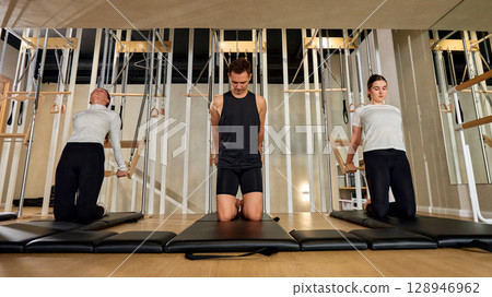 Group Class Practicing Pilates on Mats in a Modern Gym Environment Group Class Practicing Pilates on Mats in a Modern Gym Environment 128946962
