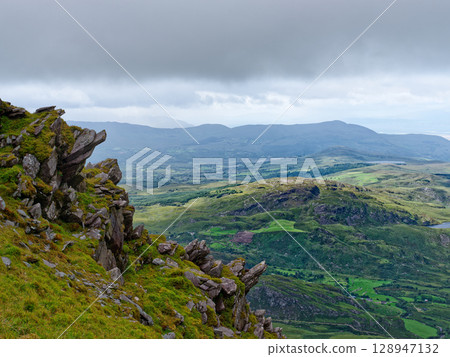 Views from high above the scenic landscape of the Coomloughra Horseshoe trail in County Kerry, Ireland, on a cloudy day. 128947132