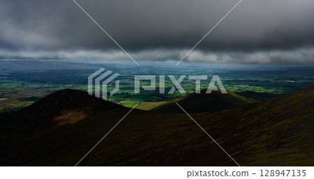 Scenic views of green valleys from the high peaks of the Coomloughra Horseshoe in Ireland. Scenic views of green valleys from the high peaks of the Coomloughra Horseshoe in Ireland. 128947135