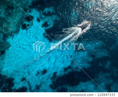 Aerial view of speed boat in clear turquoise water at sunset Aerial view of speed boat in clear turquoise water at sunset 128947333