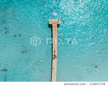 Aerial View of pier and swimming people in azure sea in summer 128947336