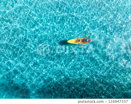 Aerial view of a kayakers paddling through vibrant blue waters 128947337