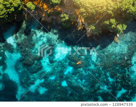 Aerial view of a kayak, azure water and green trees Aerial view of a kayak, azure water and green trees 128947339
