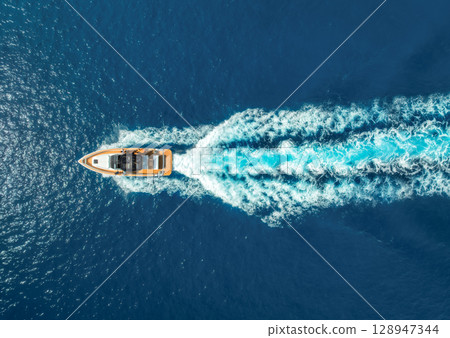 Aerial view of speed boat in clear turquoise water at sunset 128947344