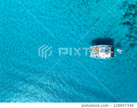 Aerial view of a yacht in the crystal-clear turquoise water 128947346