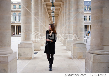 Elegant woman walking through stone colonnade in Paris 128947434