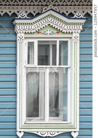Fragment of the facade of a wooden russian house of the 19th century with carved decor based on folk architecture 128947957