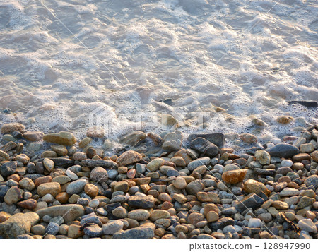 Sea wave on a stones in golden sunset light 128947990