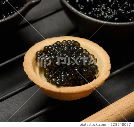 Black caviar in a round tartlet on a black table Black caviar in a round tartlet on a black table 128948057