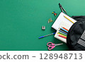 A textured green background with school supplies. 128948713