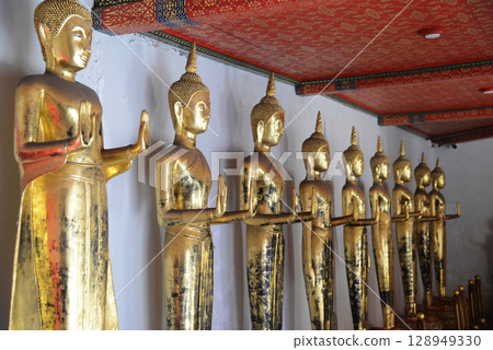 Row of standing golden Buddha at cloister in Wat Phra Chetuphon or Wat Pho. Which is one of the largest and oldest temples and is popular with both Thai and foreign tourists.. 128949330