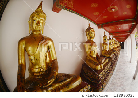 Row of sitting golden Buddha at cloister in Wat Phra Chetuphon or Wat Pho. Which is one of the largest and oldest temples and is popular with both Thai and foreign tourists. 128950023