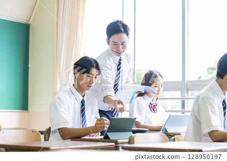 A male teacher teaching a male student A male teacher teaching a male student 128950197