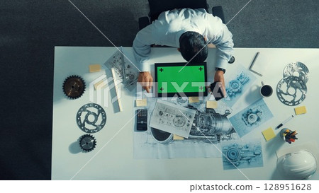 Top view of engineer look at mobile phone while working on tablet. Alimentation. 128951628