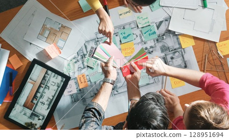 Designer team choosing color from palette while looking at blueprint. Symposium. 128951694