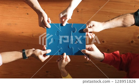 Top down view of business people assemble jigsaw puzzle on table. Convocation. 128951826