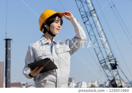 Woman in work clothes at a construction site 128951960