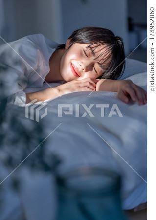 Woman lying on bed, emotional slanting light 128952060