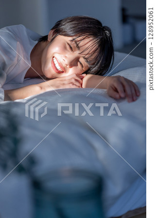Woman lying on bed, emotional slanting light Woman lying on bed, emotional slanting light 128952061