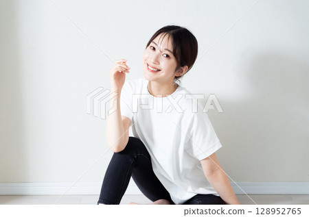 Portrait of a young woman sitting on the floor Portrait of a young woman sitting on the floor 128952765