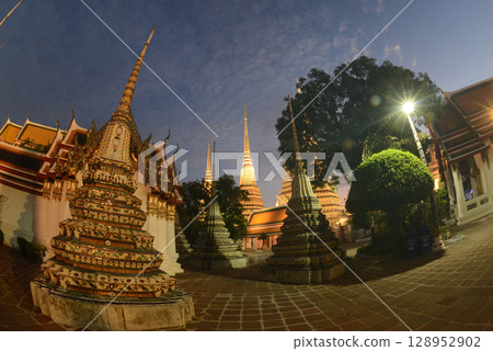 Scenic sunset time of Classic Thai architecture with pagoda in Wat Phra Chetuphon or Wat Pho. Which is one of the largest and oldest temples and is popular with both Thai and foreign tourists. 128952902