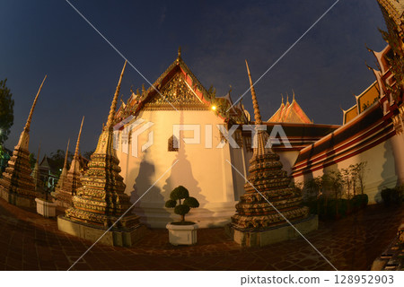 Scenic sunset time of Classic Thai architecture with pagoda in Wat Phra Chetuphon or Wat Pho. Which is one of the largest and oldest temples and is popular with both Thai and foreign tourists. Scenic sunset time of Classic Thai architecture with pagoda in Wat Phra Chetuphon or Wat Pho. Which is one of the largest and oldest temples and is popular with both Thai and foreign tourists. 128952903