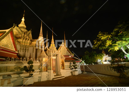 Scenic night time of Classic Thai architecture with pagoda in Wat Phra Chetuphon or Wat Pho. Which is one of the largest and oldest temples and is popular with both Thai and foreign tourists. Scenic night time of Classic Thai architecture with pagoda in Wat Phra Chetuphon or Wat Pho. Which is one of the largest and oldest temples and is popular with both Thai and foreign tourists. 128953051