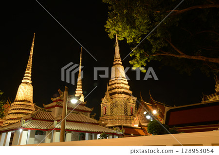 Scenic night time of Classic Thai architecture with pagoda in Wat Phra Chetuphon or Wat Pho. Which is one of the largest and oldest temples and is popular with both Thai and foreign tourists. 128953054
