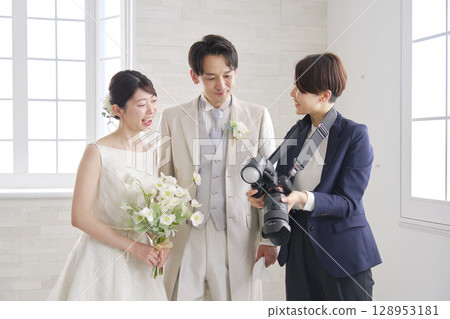 微笑的新娘和新郎與婚禮攝影師交談 128953181