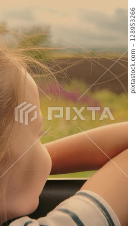 Little girl dreaming out the car window, Summer road trip with family, Fields passing by the window, Child lost in thought, Wind in her hair as she looks outside, Countryside adventure, Peaceful Little girl dreaming out the car window, Summer road trip with family, Fields passing by the window, Child lost in thought, Wind in her hair as she looks outside, Countryside adventure, Peaceful 128953266