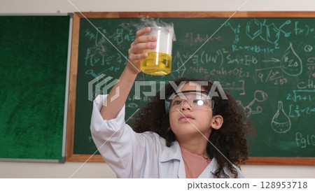 Attractive american student hold beaker and inspect colored solution. Pedagogy. Attractive american student hold beaker and inspect colored solution. Pedagogy. 128953718