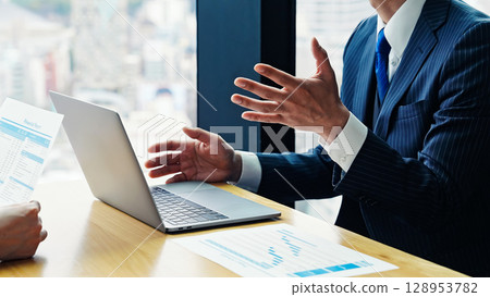 A group of business people having a meeting in an office while looking at a computer screen A group of business people having a meeting in an office while looking at a computer screen 128953782