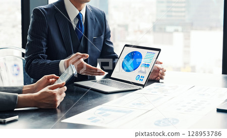 A group of business people having a meeting in an office while looking at a computer screen A group of business people having a meeting in an office while looking at a computer screen 128953786